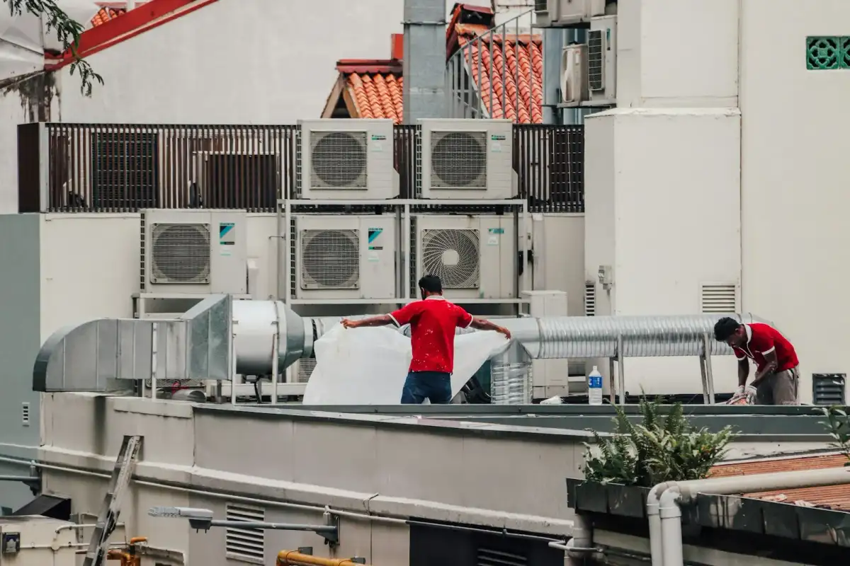 Technician servicing an outdoor AC condenser unit on a Dubai rooftop